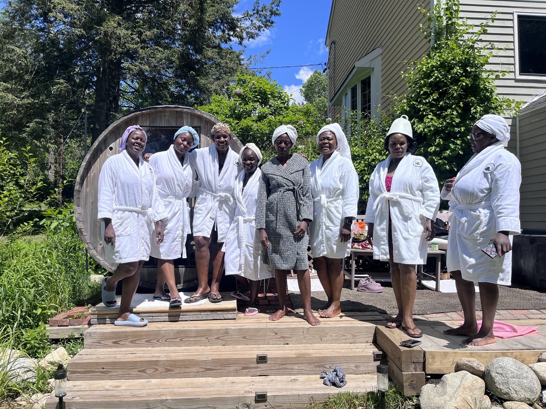 A joyful group in robes and towels in front of the barrel sauna