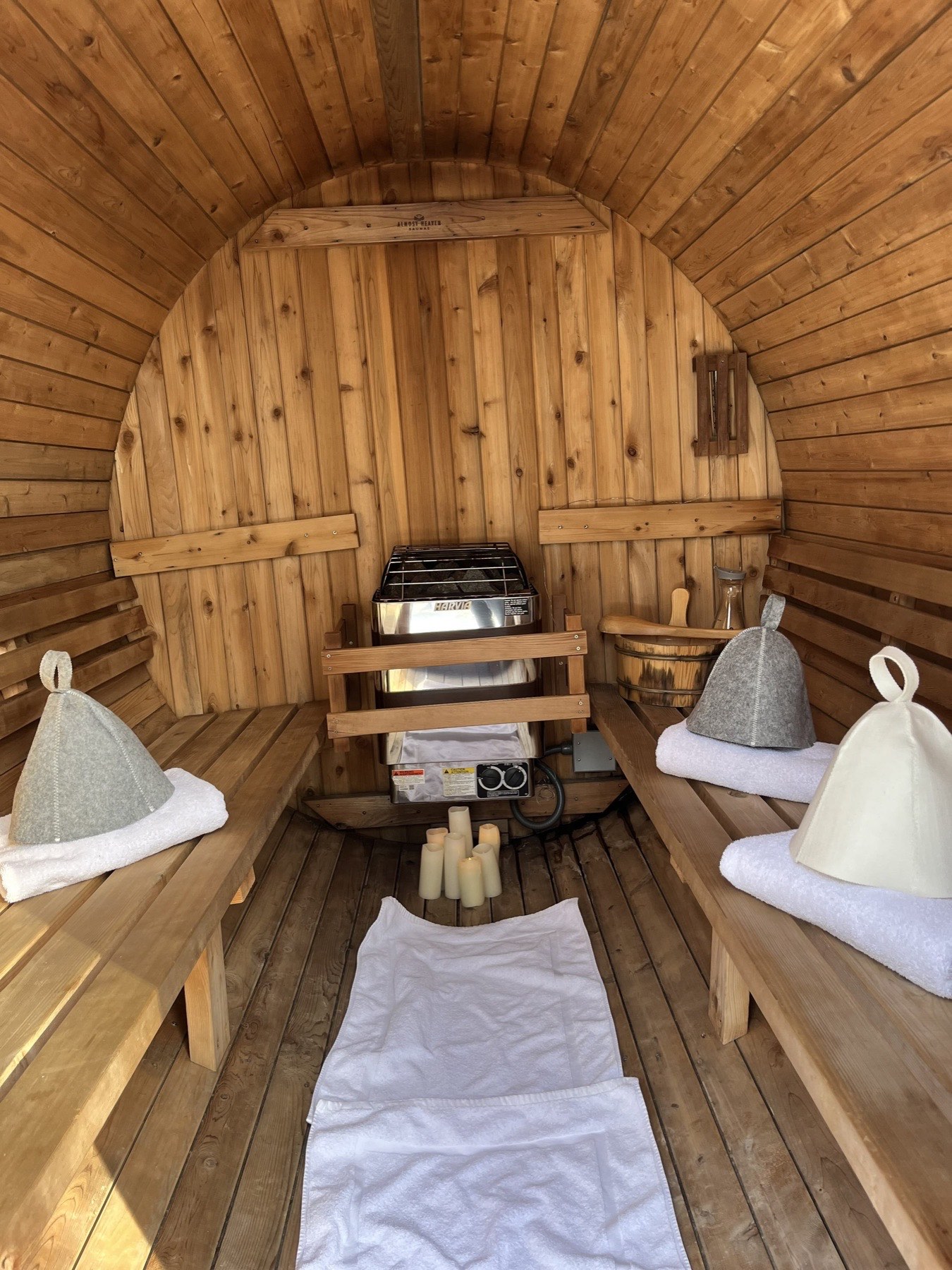 Inside the cedar barrel sauna: benches with towels and felt sauna hats