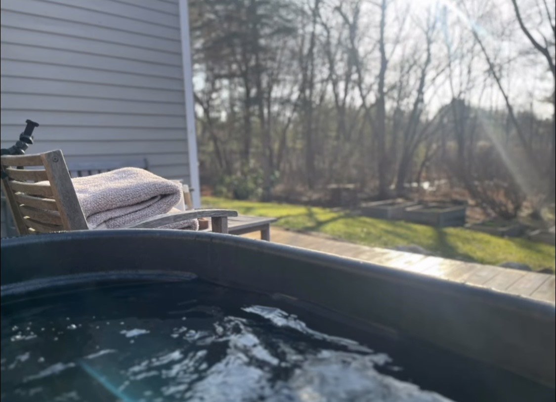 The cold plunge tub outdoors, looking over the yard and trees